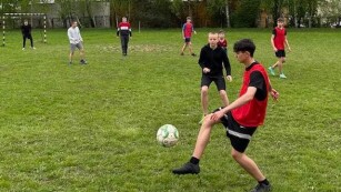 Chłopcy grają w piłkę nożną na boisku trawiastym