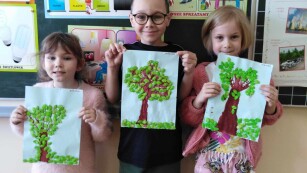 Trójka dzieci prezentuje prace plastyczną Drzewo